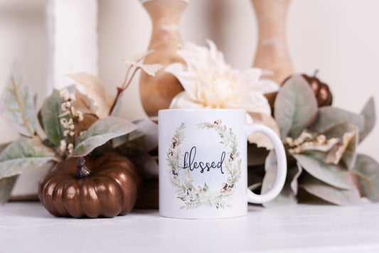 Close-up of ceramic fall mugs with watercolor wreaths and script text blessed