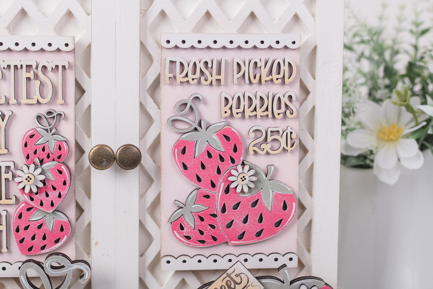 Decorative sign with pink strawberries and text on a white background