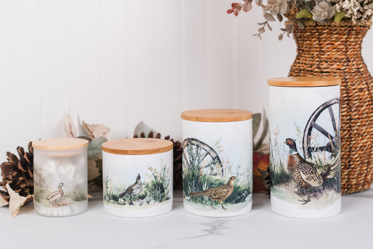 Set of ceramic bathroom canisters with wooden lids featuring game bird designs on a white surface.