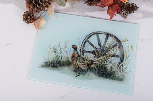 Glass prep board with a pheasant and wagon wheel design on a white surface.
