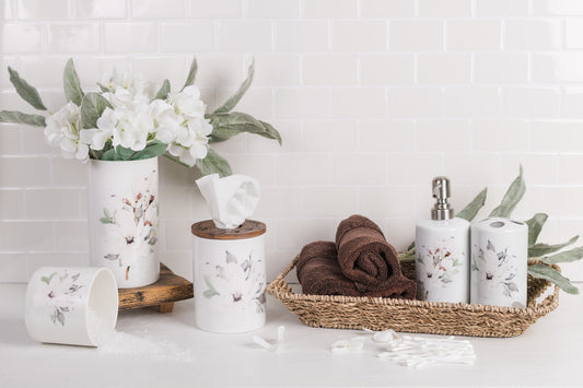 Bathroom setting with toiletries, towels, and magnolia canisters on a white tiled wall background.