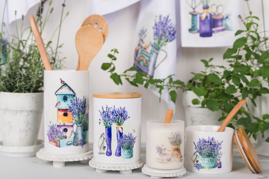 Set of ceramic containers with artistic designs on a white surface with plants in the background