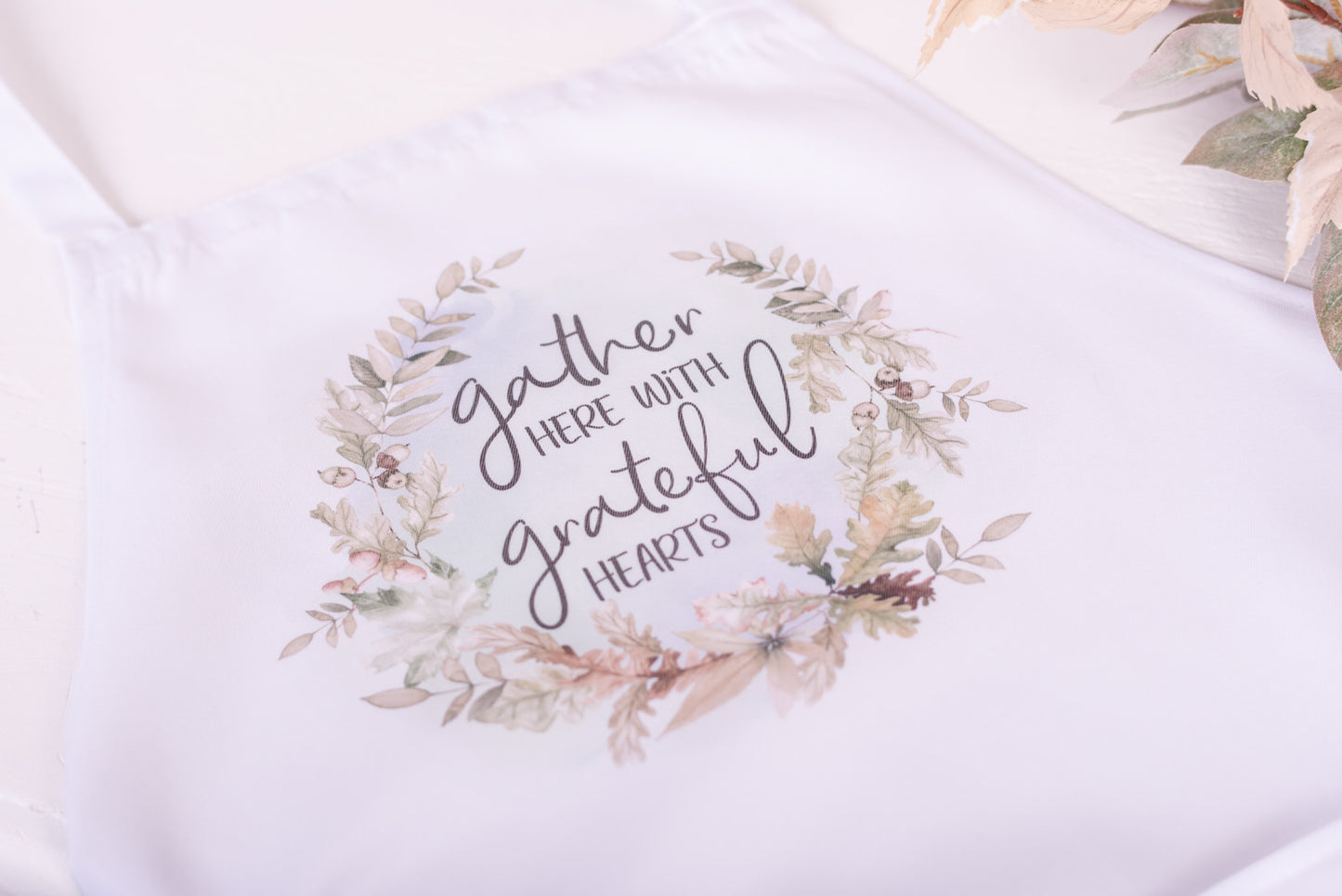 Thanksgiving apron with ‘Gather Here with Grateful Hearts’ message and oak leaf wreath