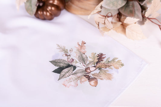 White fall apron with watercolor acorn and leaf design in bottom corner – Woodland Collection