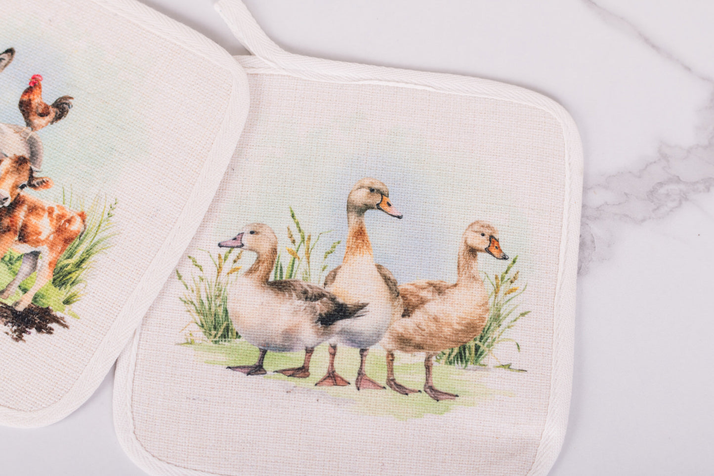 Two pot holders with duck design on a marble surface