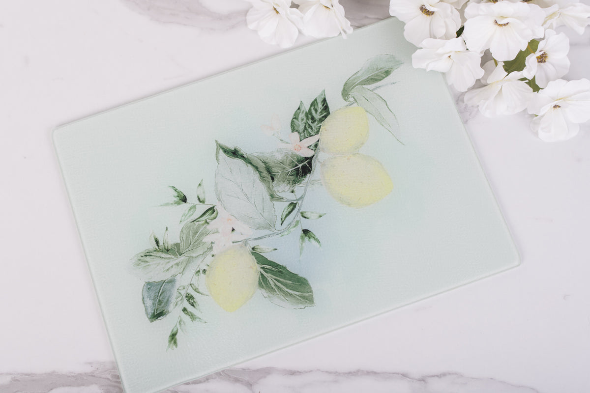 Glass cutting board with lemon and leaf design on a marble surface