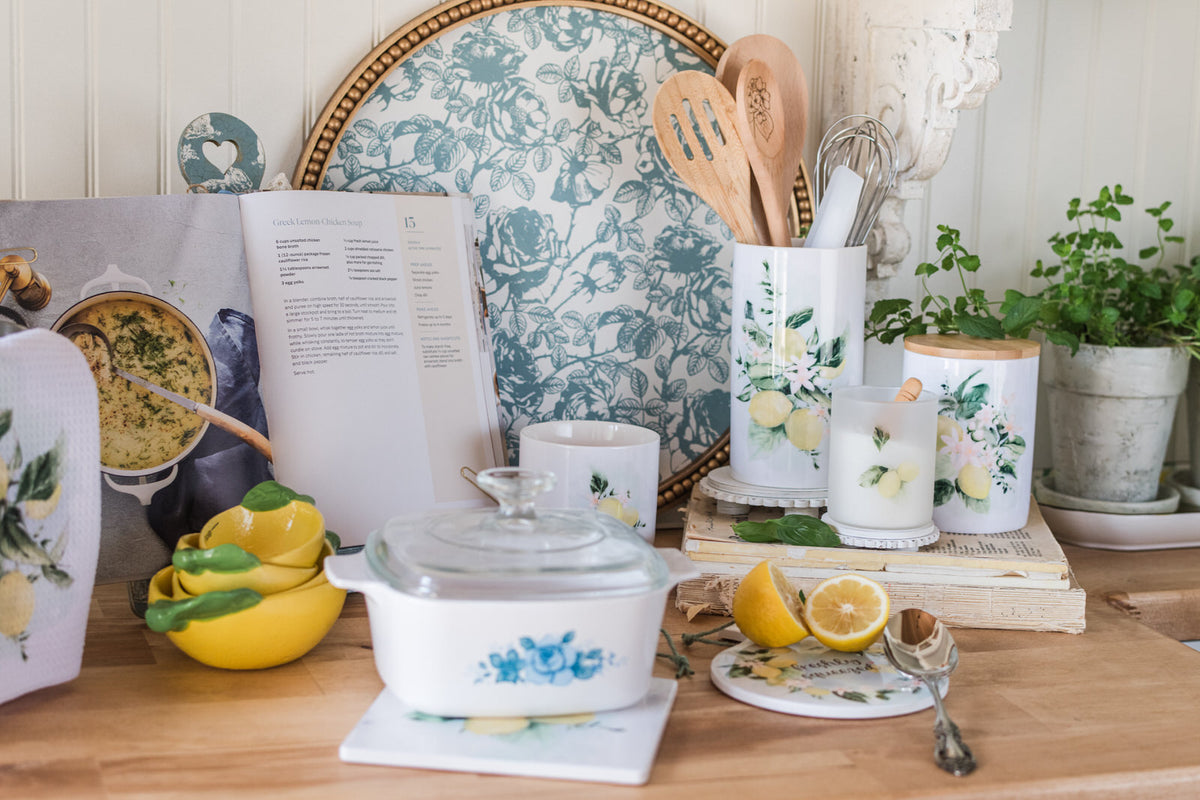 Kitchen counter with cookbooks, lemons, and kitchen utensils on a wooden surface.