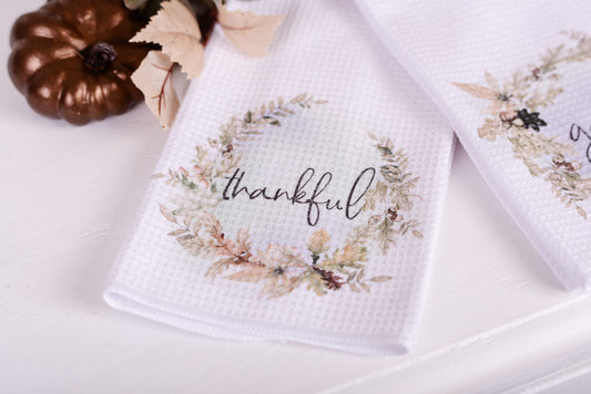 Neutral fall tea towels with autumn floral wreaths with the word thankful
