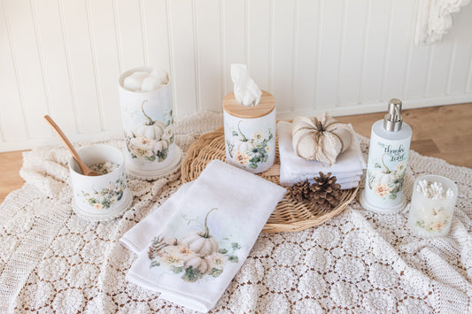 Bathroom accessories include towels, candles, and a soap dispenser with floral and pumpkin designs on a textured surface.
