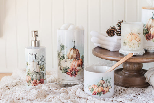 Decorative bathroom jars and a soap dispenser with autumn-themed designs on a textured surface.