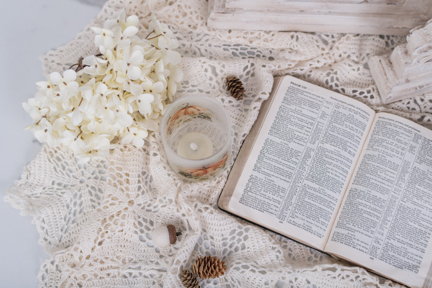 Open book on a textured surface with flowers and a candle