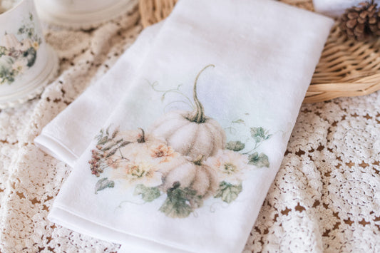 White towel with pumpkin and floral design on a textured surface