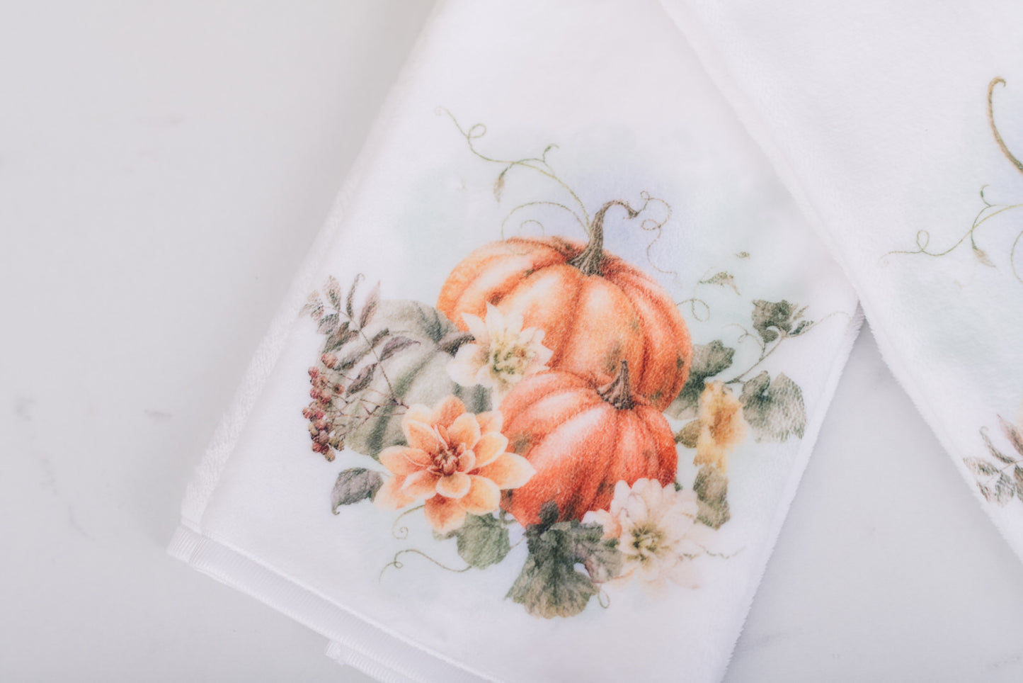 Decorative hand towel with pumpkins and floral design on a white background