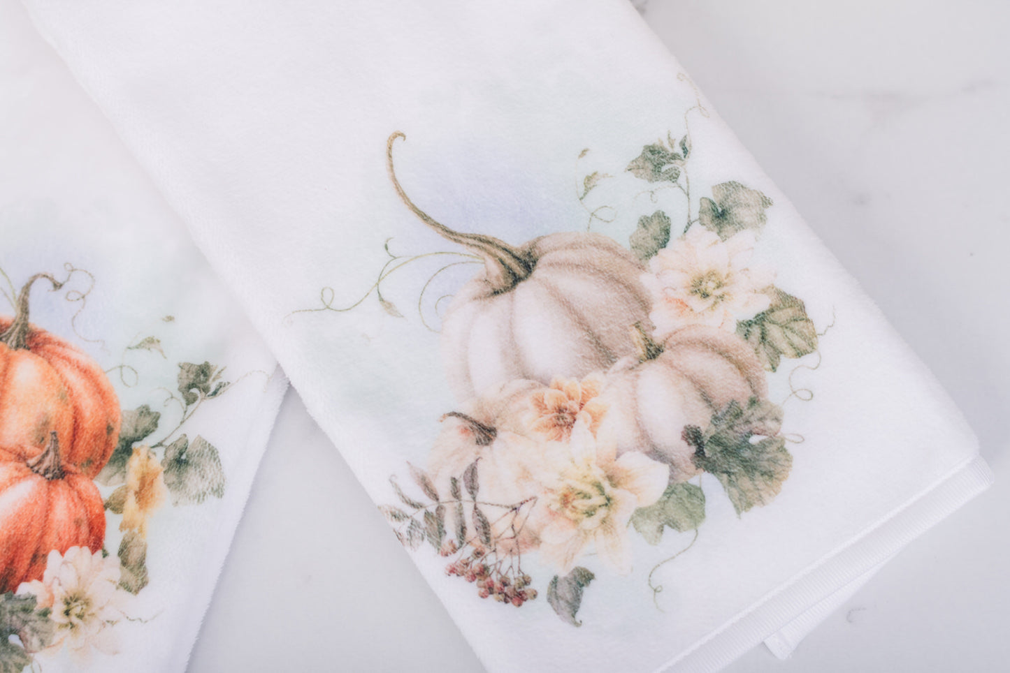 Set of two decorative towels with pumpkins and floral designs on a white background