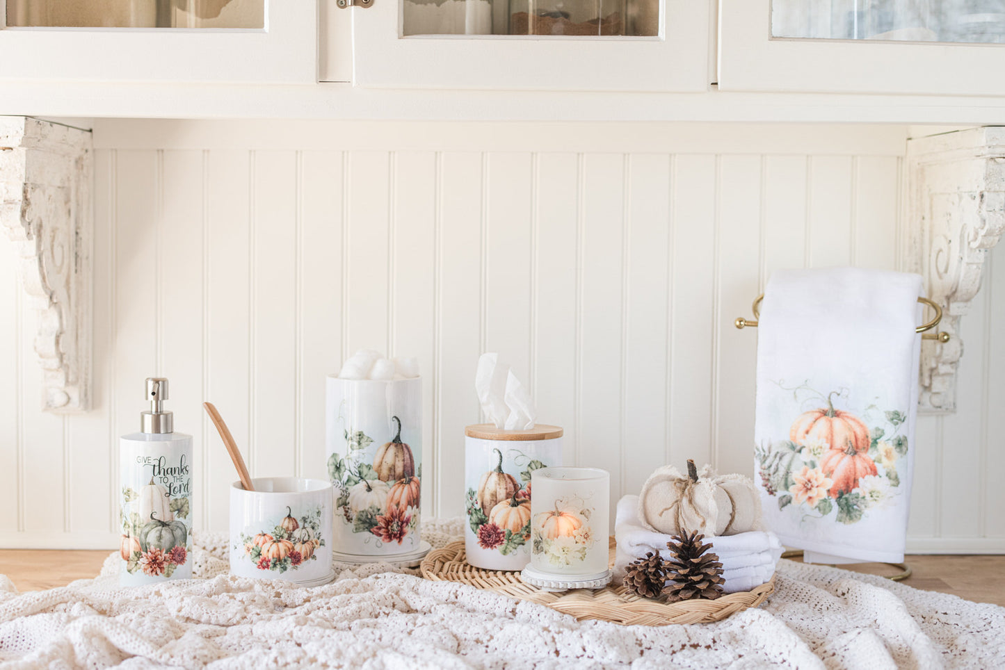 Bathroom canisters are displayed alongside other items, including candles, a towel, and pumpkins, on a table with a white background.