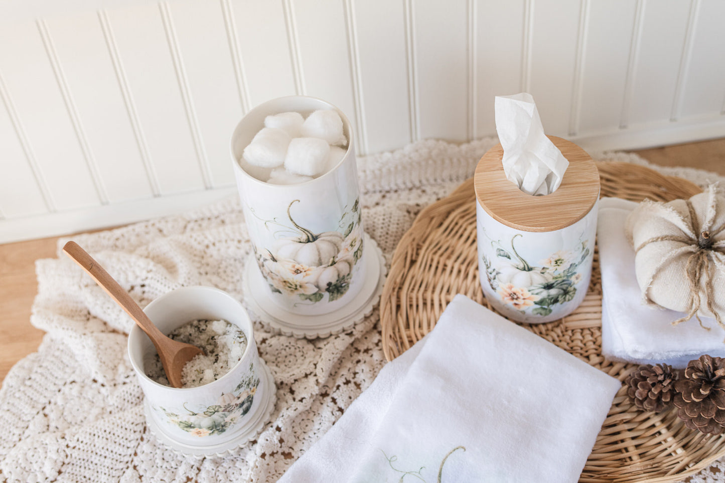 Decorative storage for a bathroom, including canisters and a tissue holder, on a textured surface with a white background.