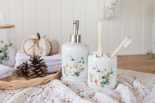 Bathroom set with fall pumpkin-themed soap dispenser, toothbrush holder, and towels on a textured surface.