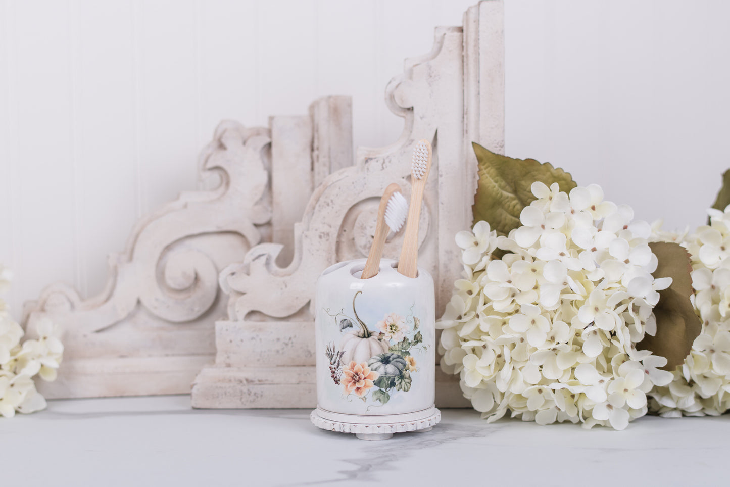 Ceramic toothbrush holder with fall pumpkin floral artwork in bathroom