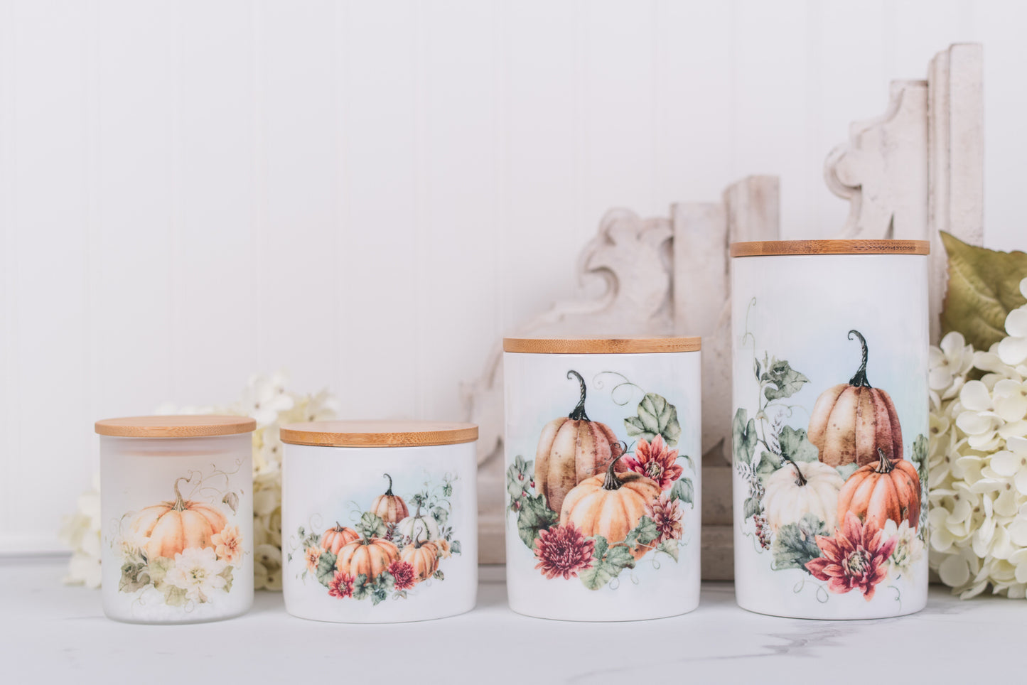 Set of ceramic canisters with pumpkin and floral designs on a white surface.