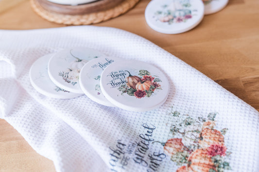 Decorative coasters with autumn designs on a white towel.
