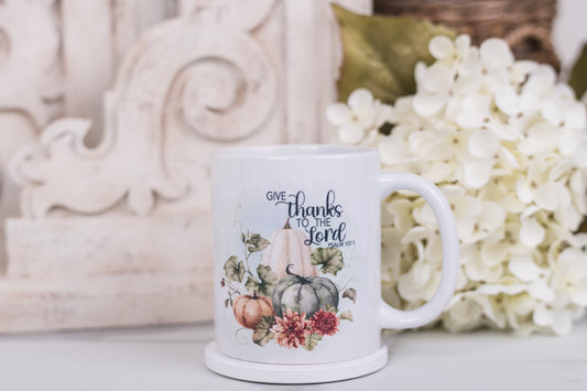 Mug with 'Give thanks to the Lord' text and autumn design on a decorative background
