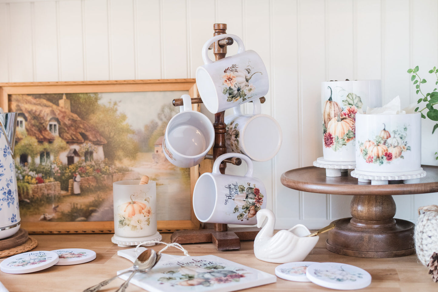 Decorative items including mugs, candles, and a painting on a wooden surface.