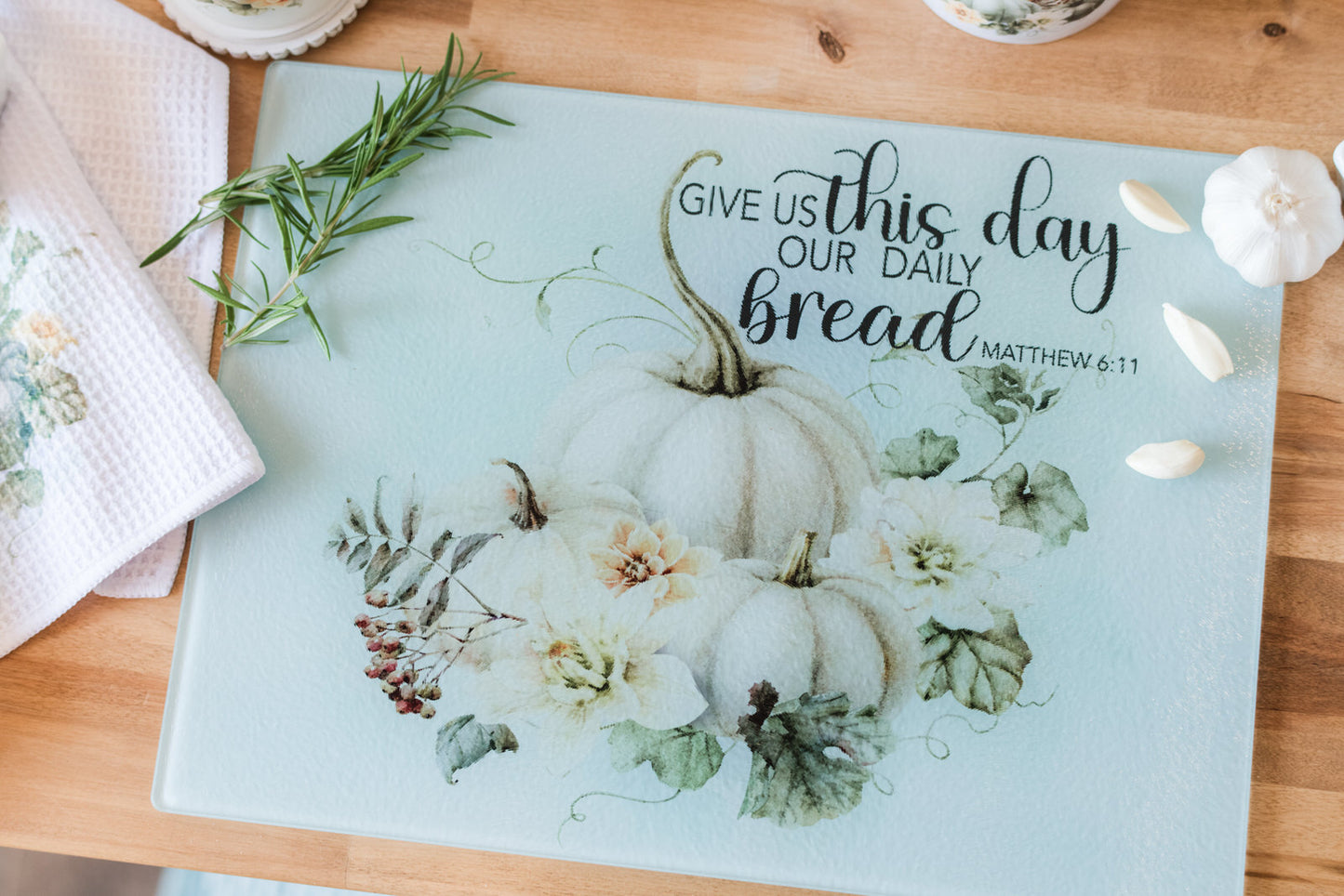 Glass cutting board with a fall pumpkin design and scripture Matthew 6:11 on a butcher block