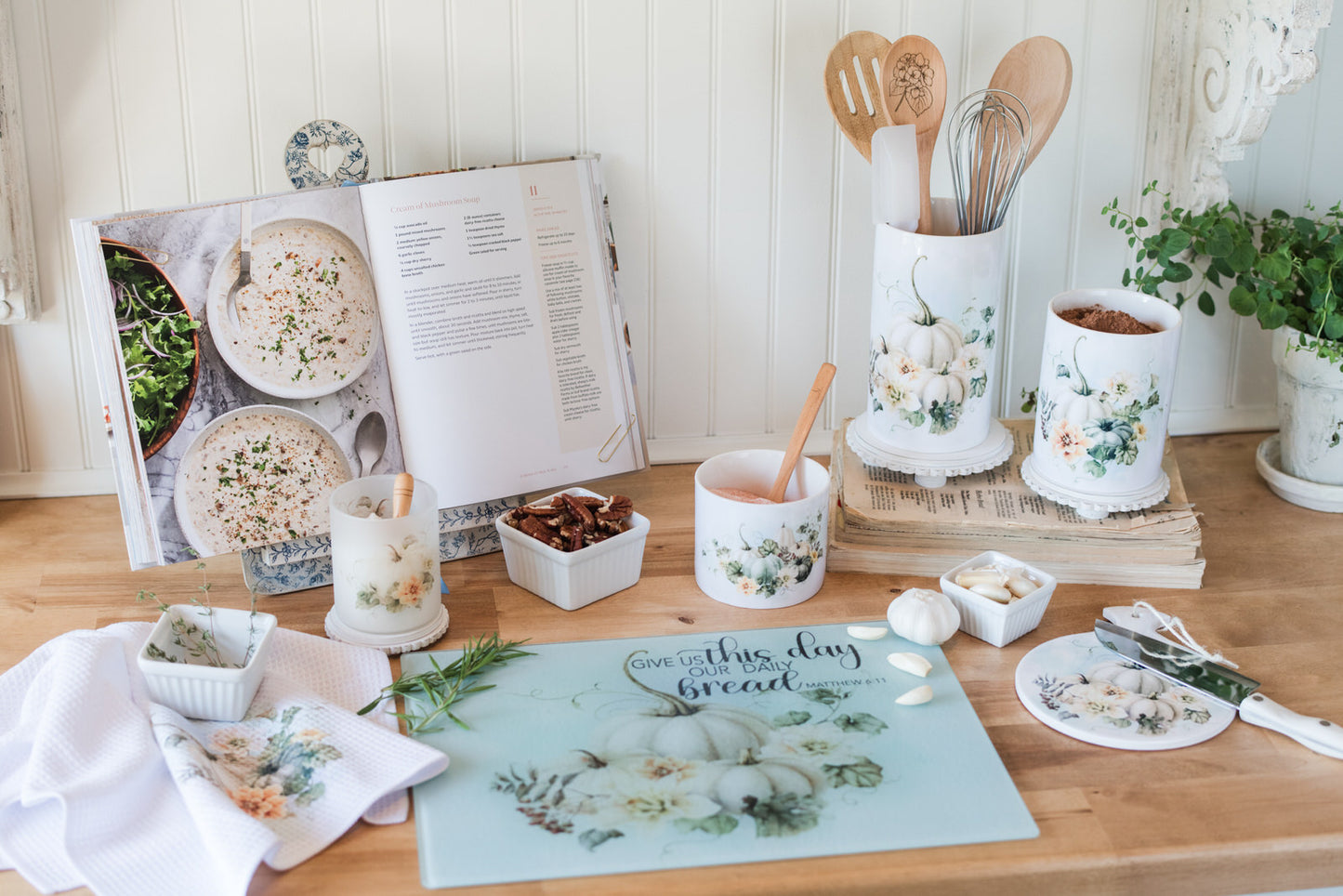Kitchen counter with cookbooks, mugs, and kitchen utensils on a wooden surface.