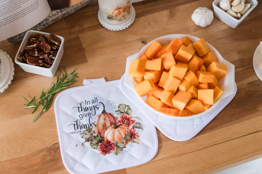 Diced squash in a casserole dish on fall pot holders, sitting on a butcher block.