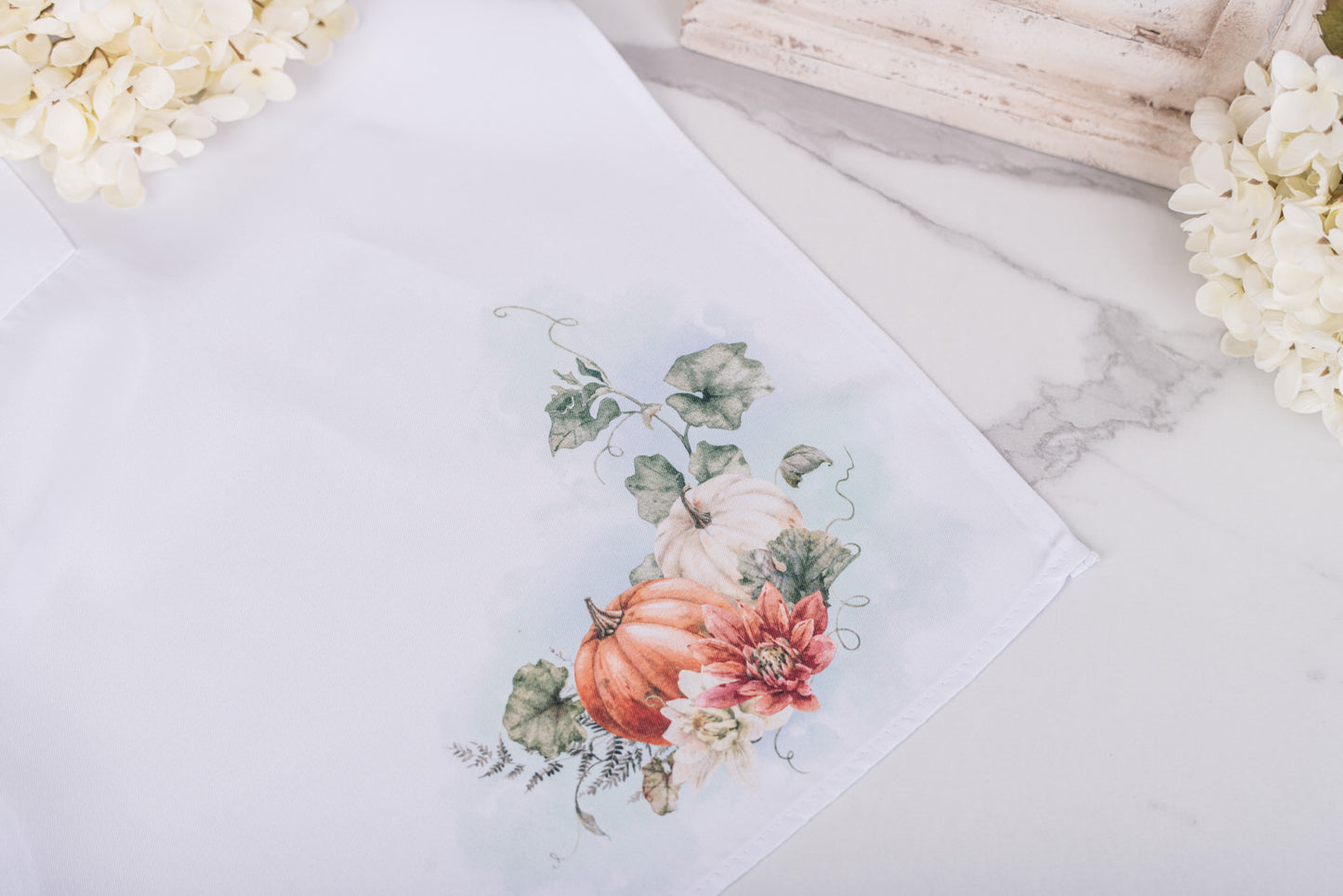 White apron with warm fall pumpkin design in lower corner