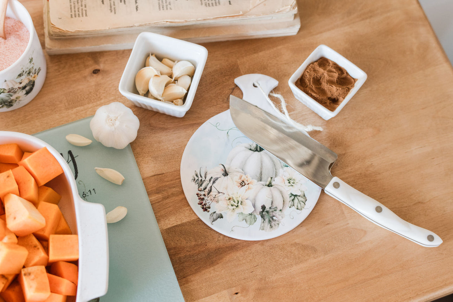 pumpkin and floral fall spoon rest on a butcher block with ingredients and a knife