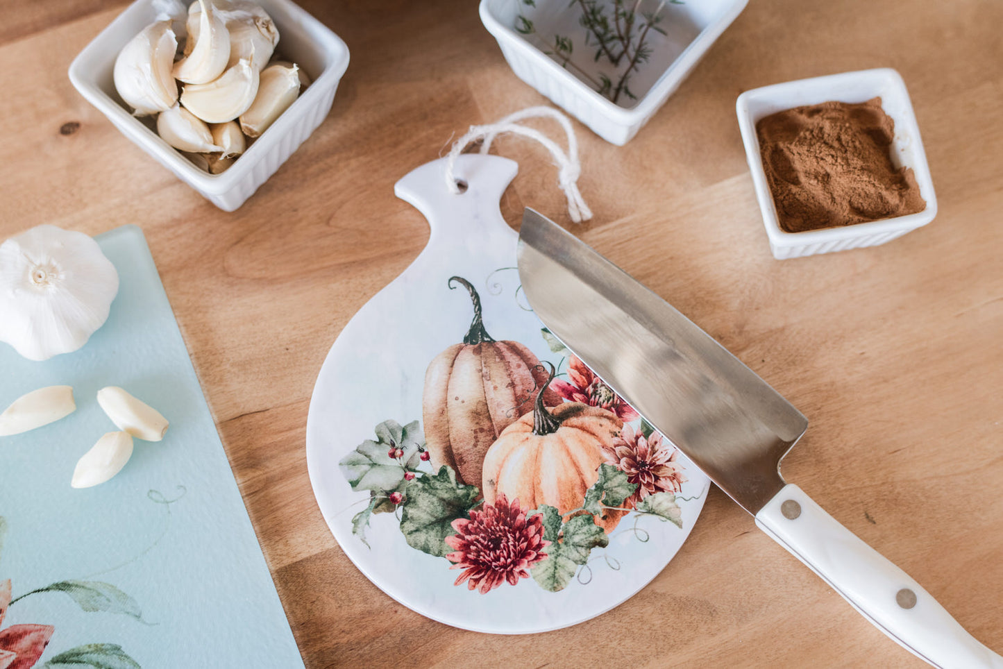 Decorative spoon rest with pumpkins and flowers on a wooden table with ingredients.