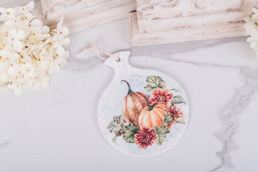 Spoon rest with pumpkins and flowers on a marble surface with flowers and corbels in the background