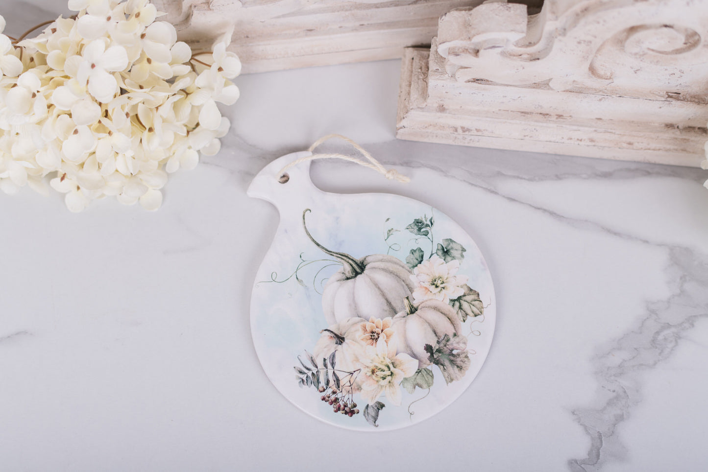 Decorative round spoon rest with pumpkins and flowers on a marble surface