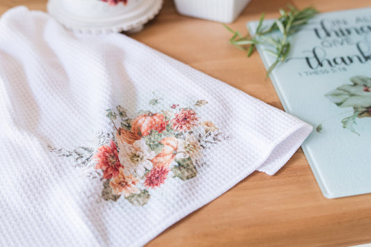 Cozy pumpkin tea towels with mums, zinnias, and fall greenery on a butcher block
