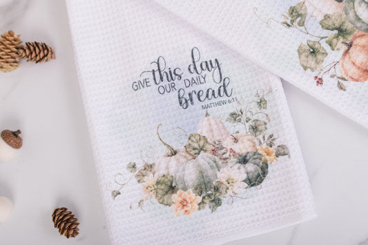 Floral towel with 'Give this day our daily bread' text on a white background