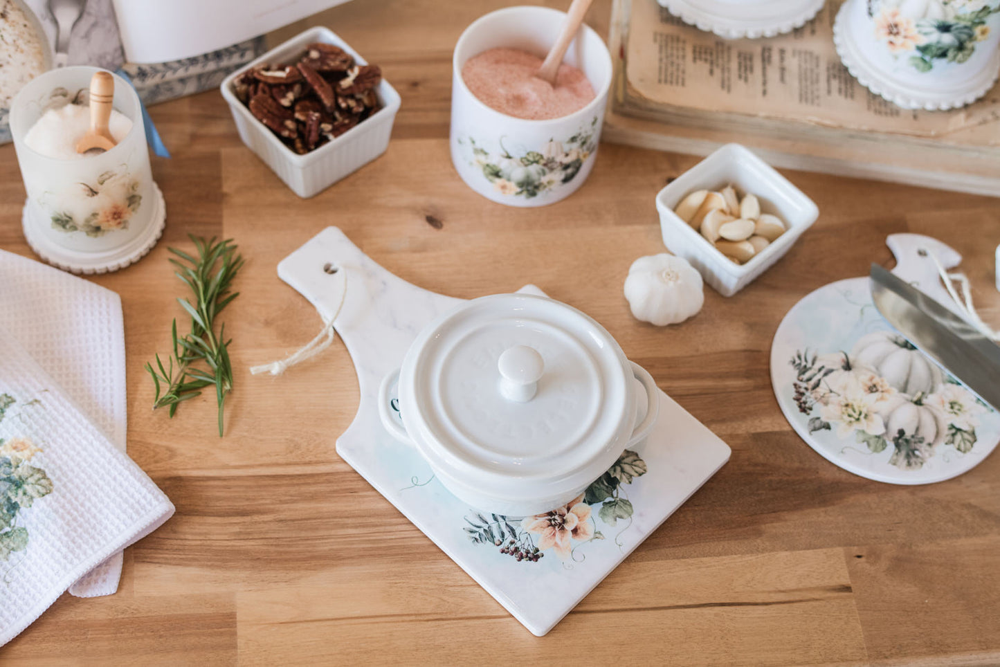 White ceramic pot with lid on a Autumn kitchen hot pad with scripture and neutral fall colors.
