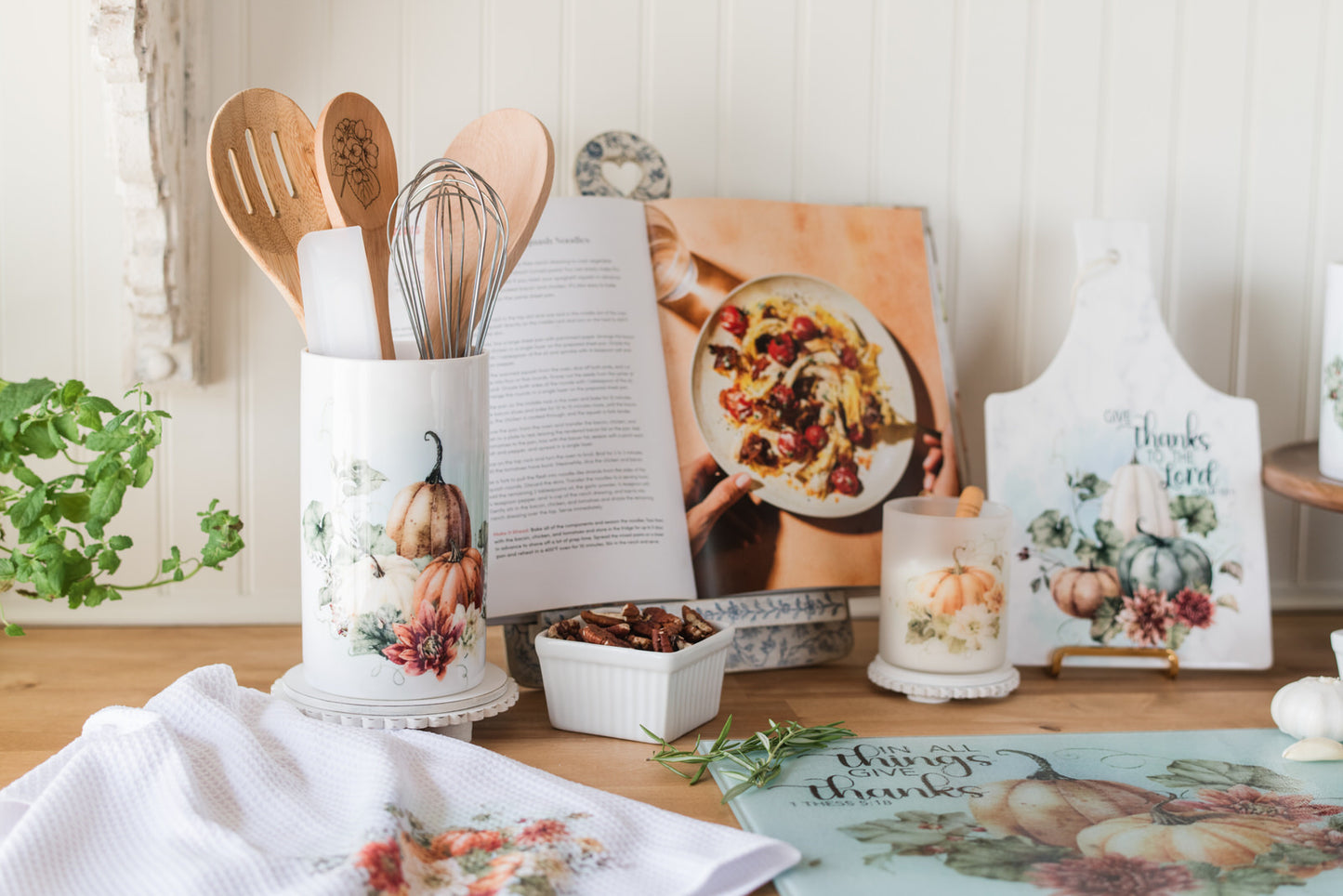 Warm fall utensil holder with orange pumpkins and florals in a kitchen baking area