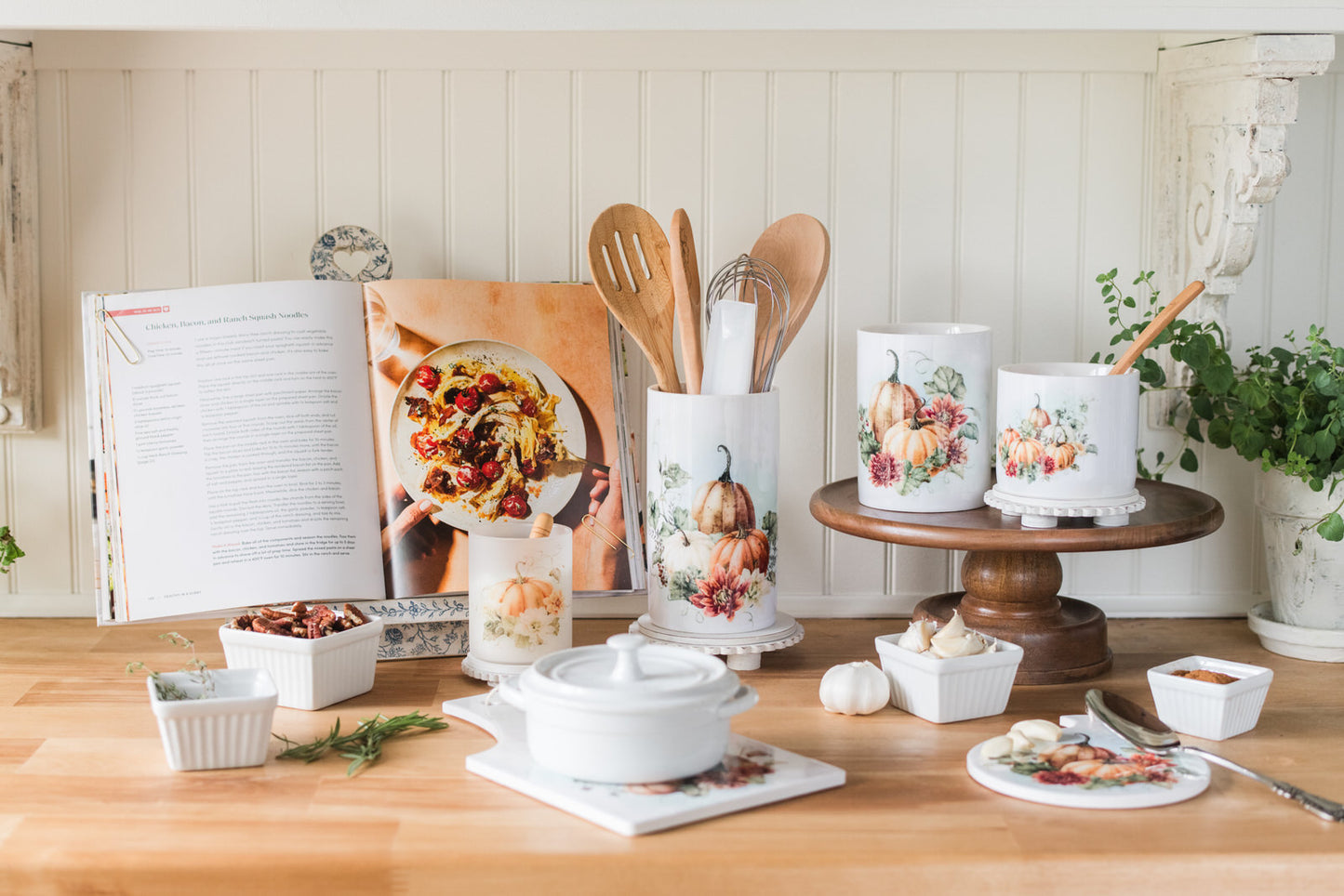 fall kitchen counter with cookware, utensils, and decorative items on a wooden surface.