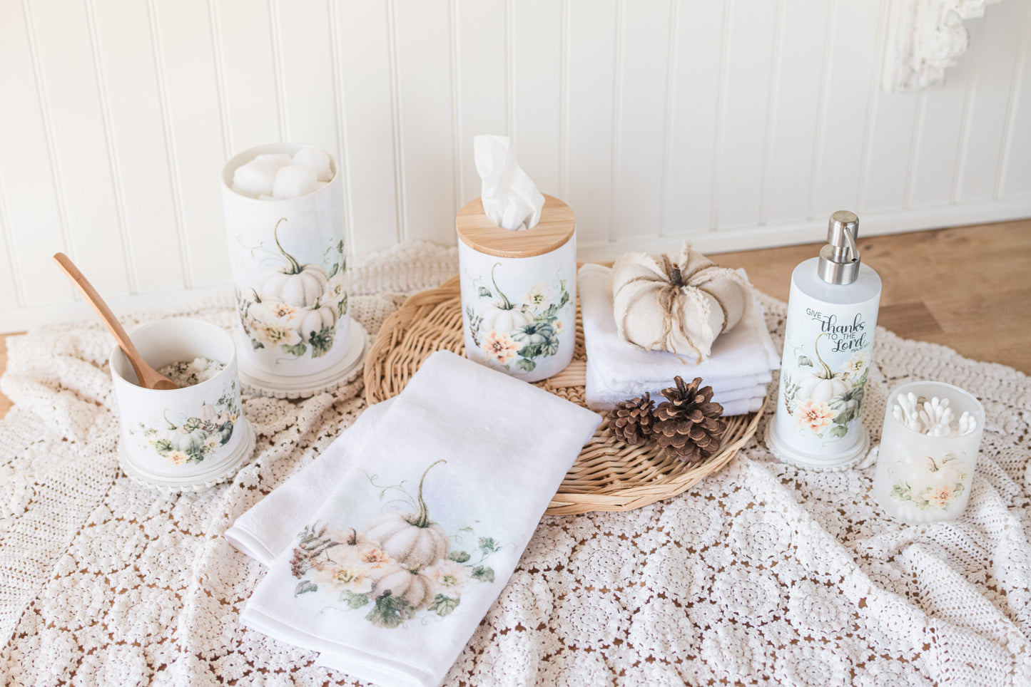 Fall bathroom accessories, including towels, tissue holder, soap dispenser, bathroom jars and decorative items, on a textured surface.