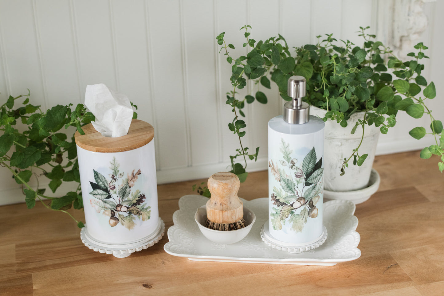 Decorative bathroom set with floral-patterned canisters and soap dispenser on a wooden surface.