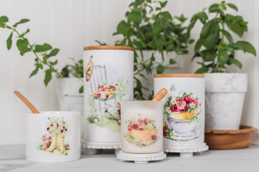 Set of decorative canisters with floral designs on a surface with plants in the background