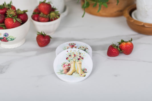 Coasters with floral and boot design on a table with strawberries