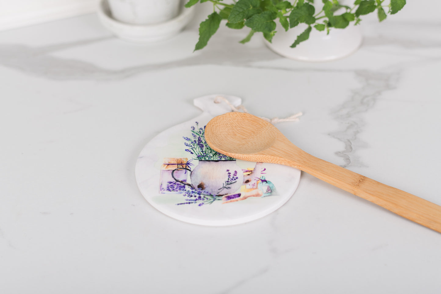trivet with floral design and wooden spoon on marble surface