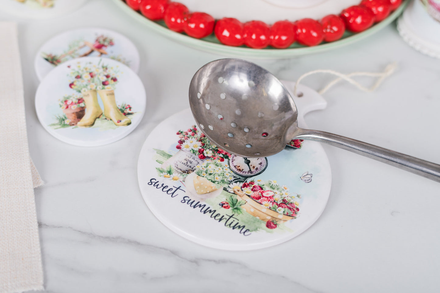 Watercolour strawberry spoon rest on a marble surface.