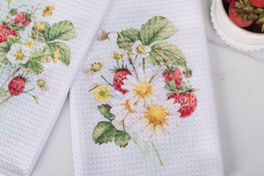 White towels with floral and strawberry design on a light gray background