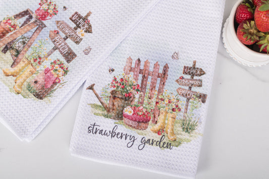 Kitchen towel with garden-themed design and 'strawberry garden' text on a white surface.