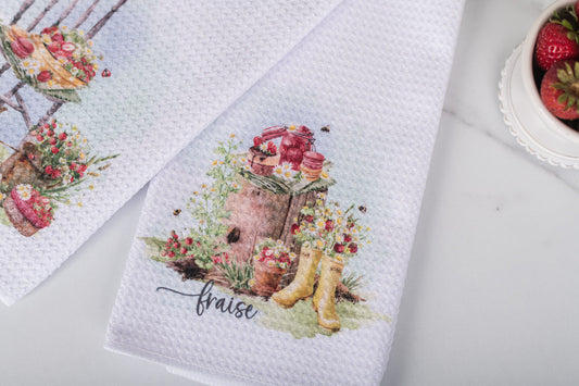 Decorative kitchen towel with floral design and 'fraise' text on a white surface.