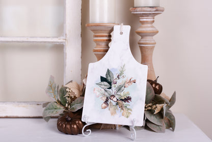 Ceramic fall kitchen, trivet sitting on an easel styled with fall leaves and pumpkins