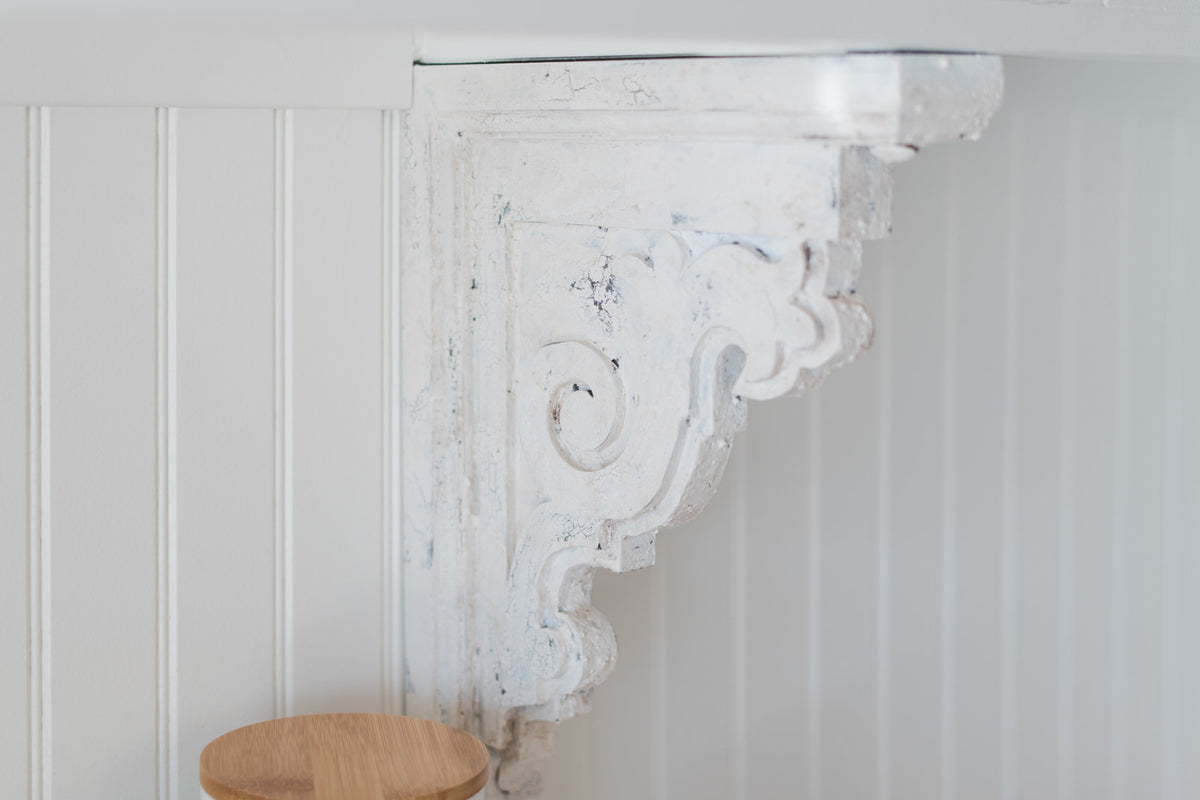 Decorative white corbel on a white bead board wall